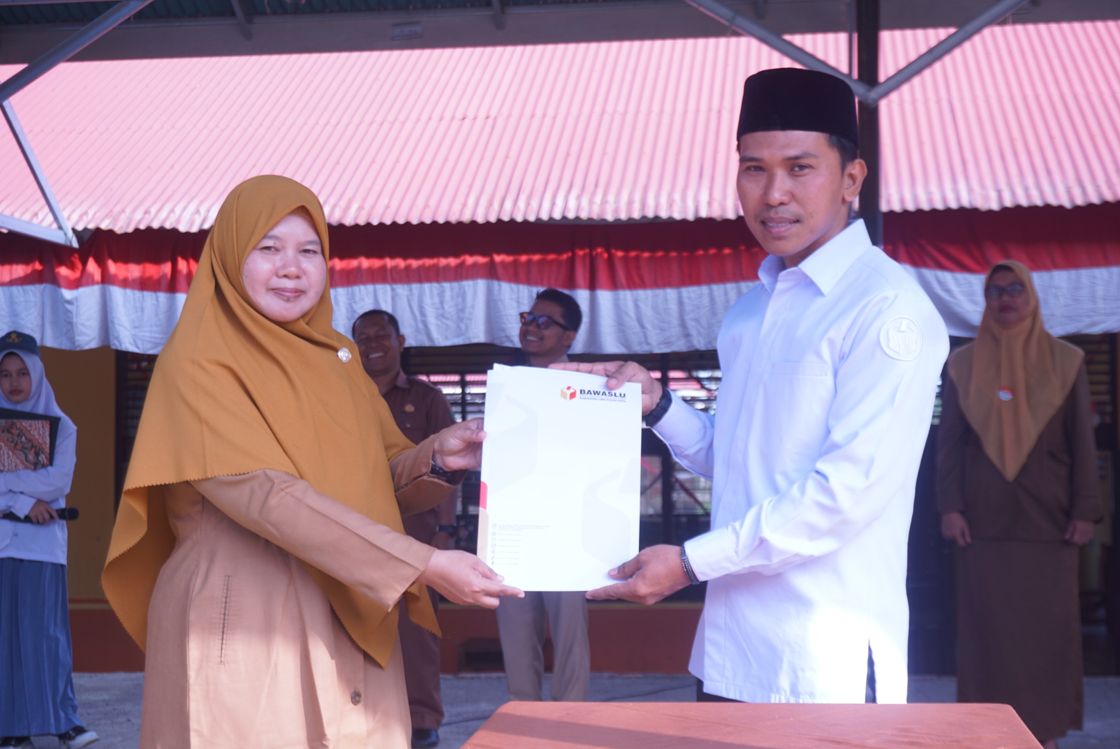 Dapit Alexsander selaku Anggota Bawaslu Kabupaten Lima Puluh Kota saat menyerahkan berkas Perjanjian Kerja Sama (PKS) kepada Kepala Sekolah SMA N 1 Situjuah Limo Nagari Kabupaten Lima Puluh Kota, Fita Fatimah, (31/8).